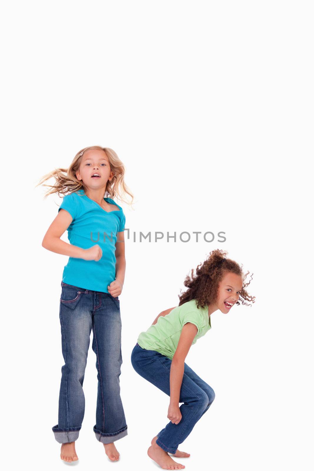 Portrait of happy girls jumping against a white background