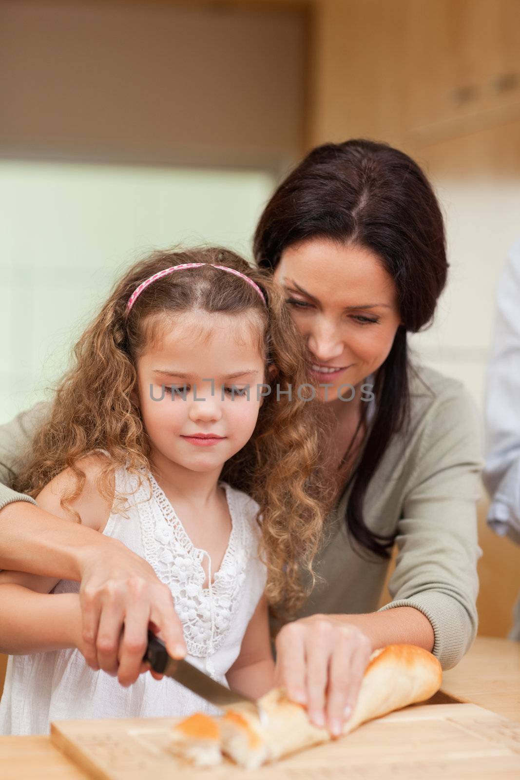 Mother and daughter cutting bread into slices together