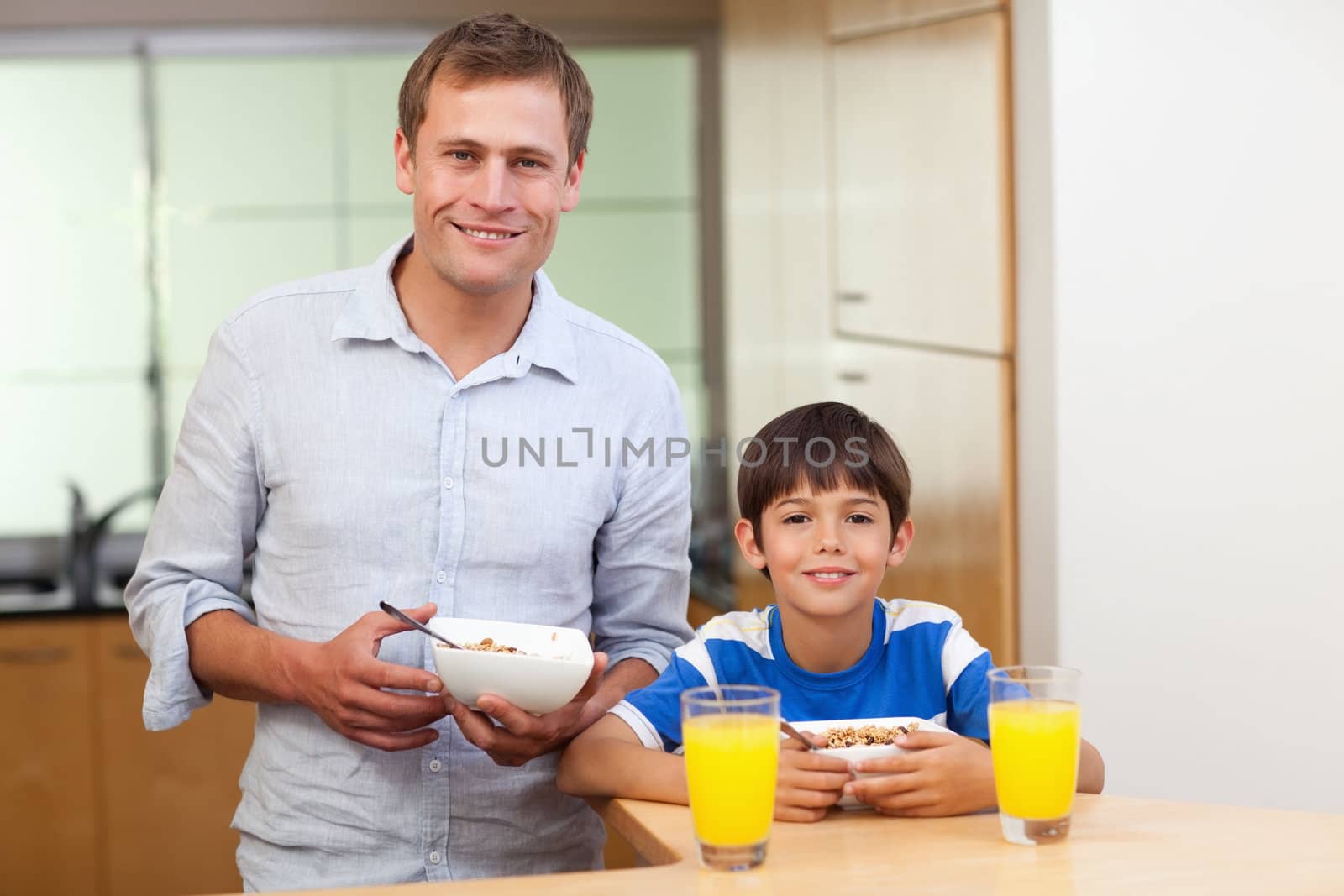 Father and son having cereals and orange juice together