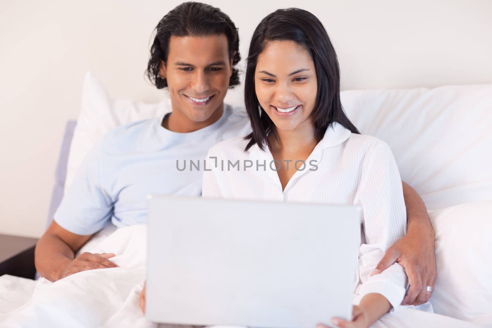 Young couple sitting on the bed with their laptop