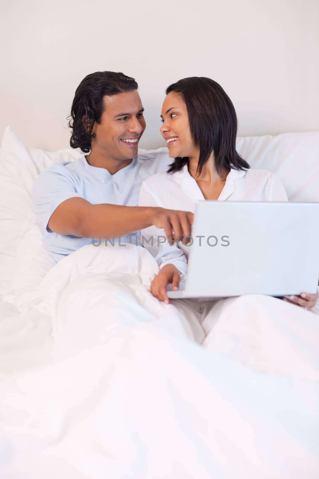 Young couple sitting on the bed surfing the internet