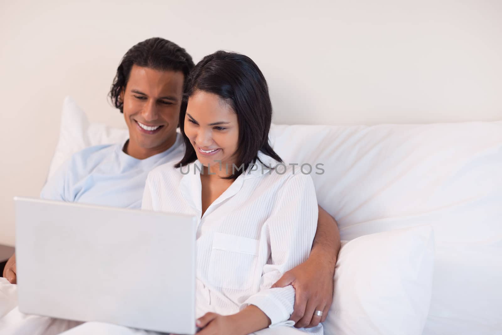 Young couple sitting on the bed using the internet