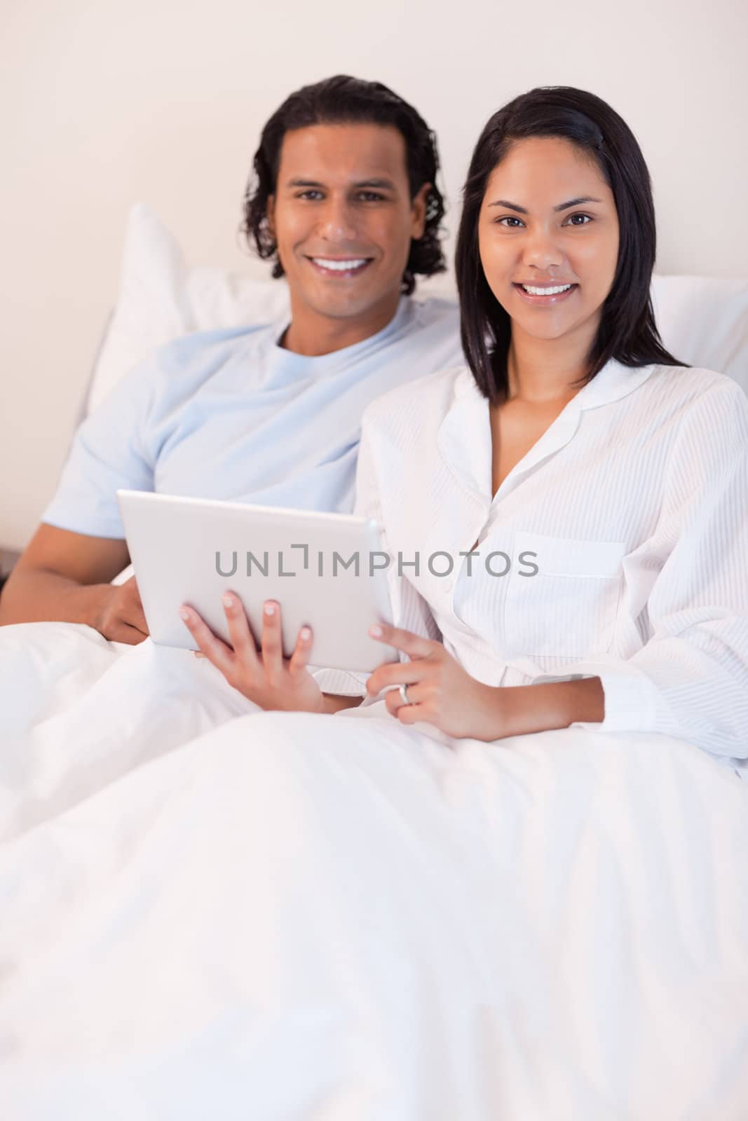 Young couple using tablet pc in their bed