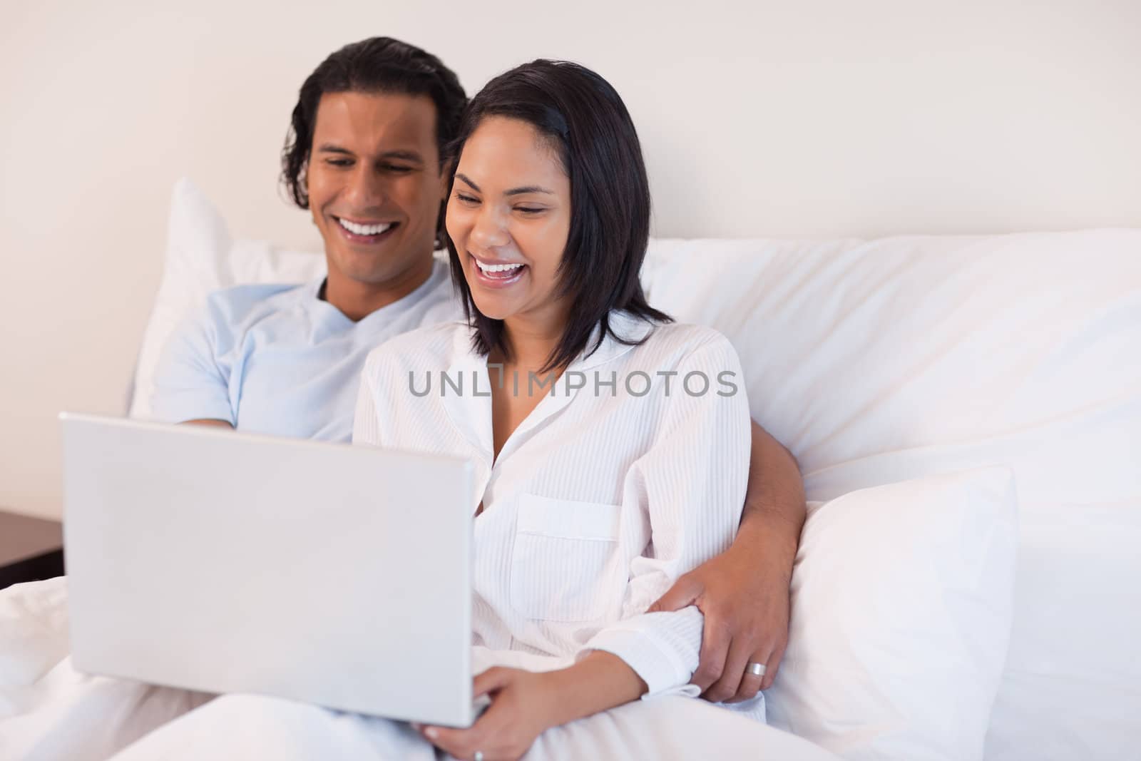 Young couple using their laptop while sitting on the bed