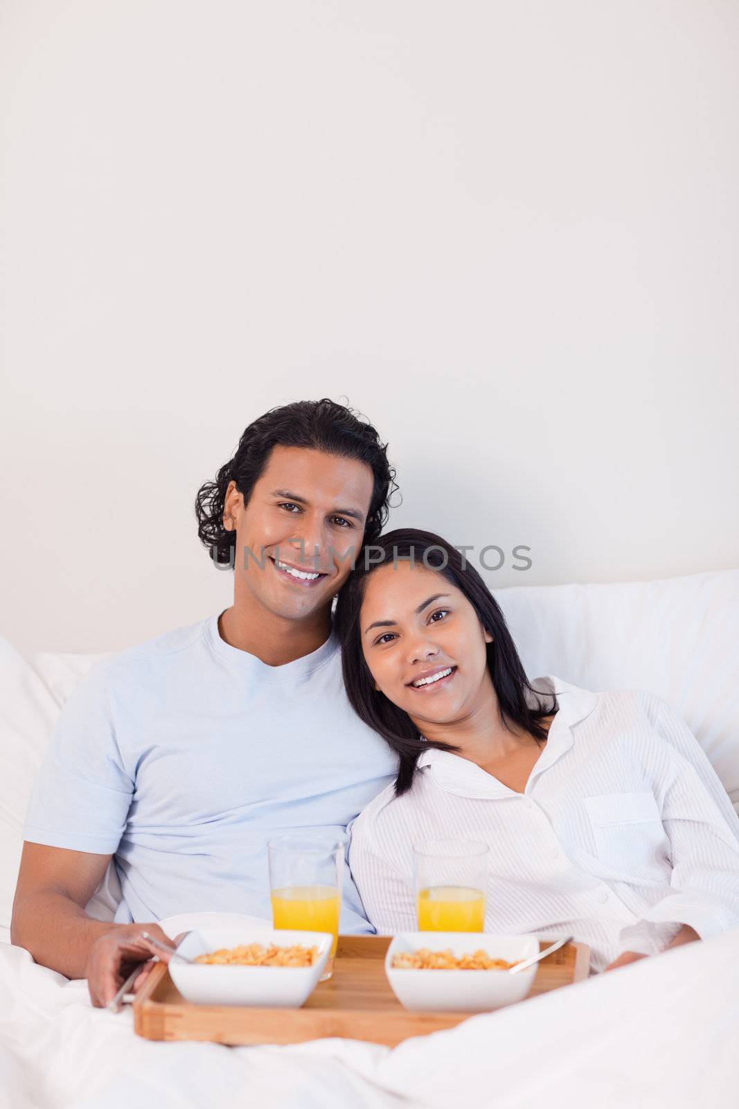 Happy young couple having breakfast in the bed