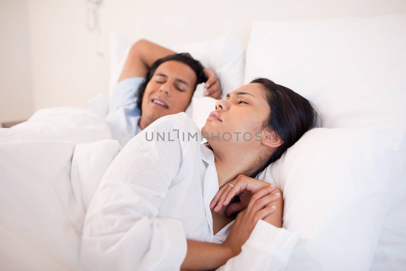 Young woman being woken up by snoring boyfriend