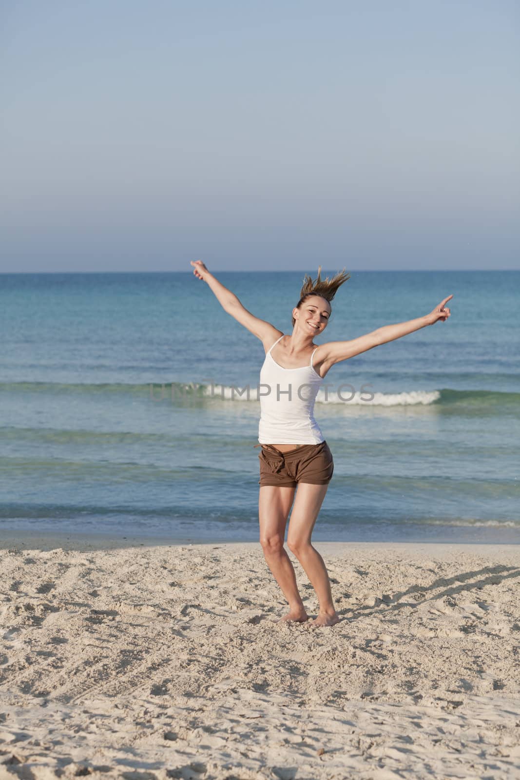 Girl young cheerful woman jumping in the air on the beach in the sand in the morning on the sea in summer vacation