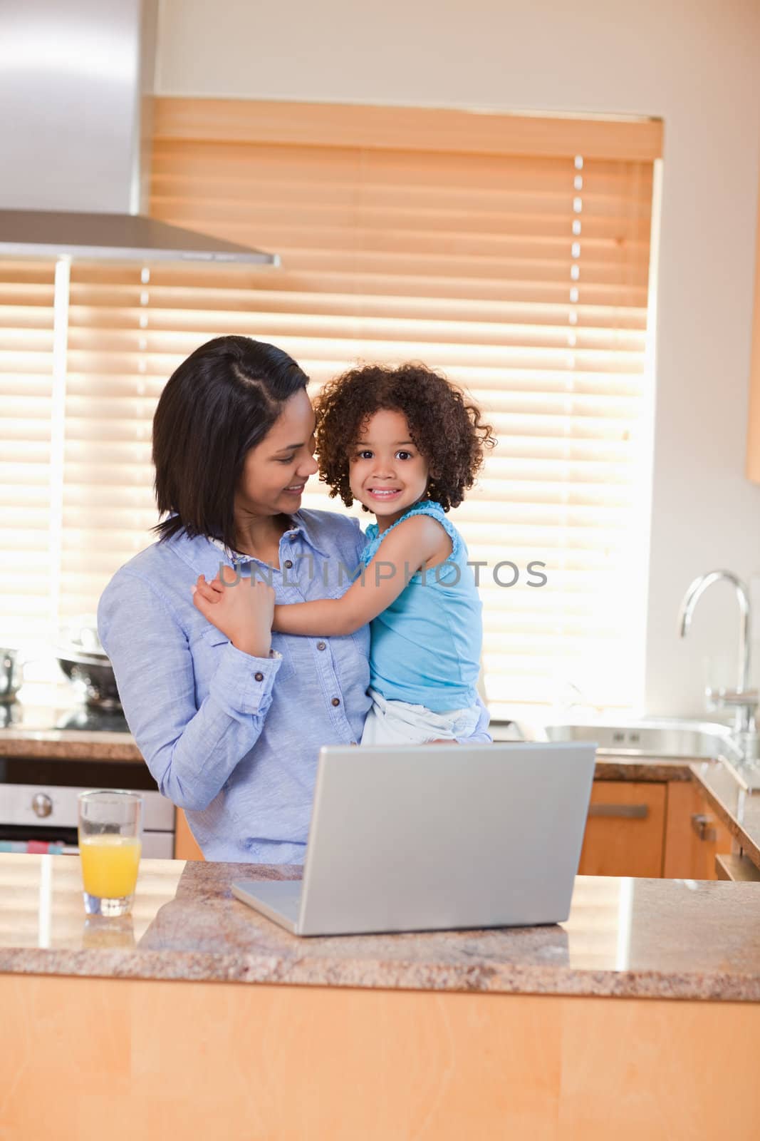 Young mother and daughter with notebook in the kitchen