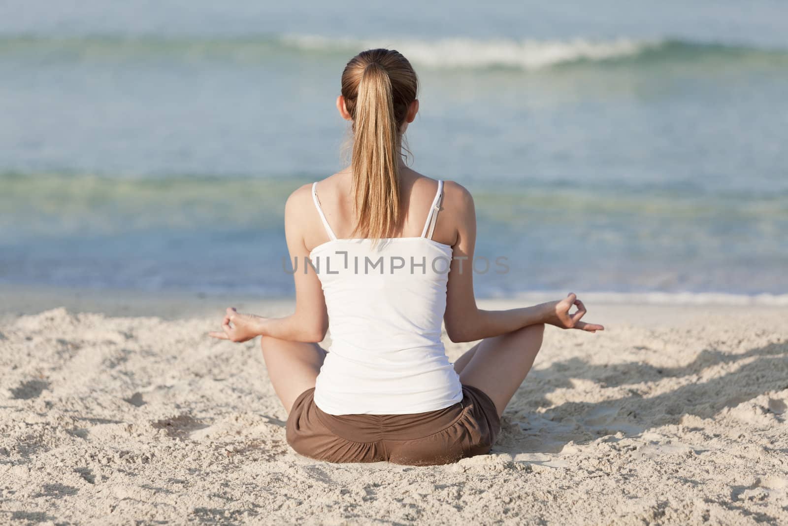 Young sporty woman doing sport yoga on the beach in the sand on the beach in the sun