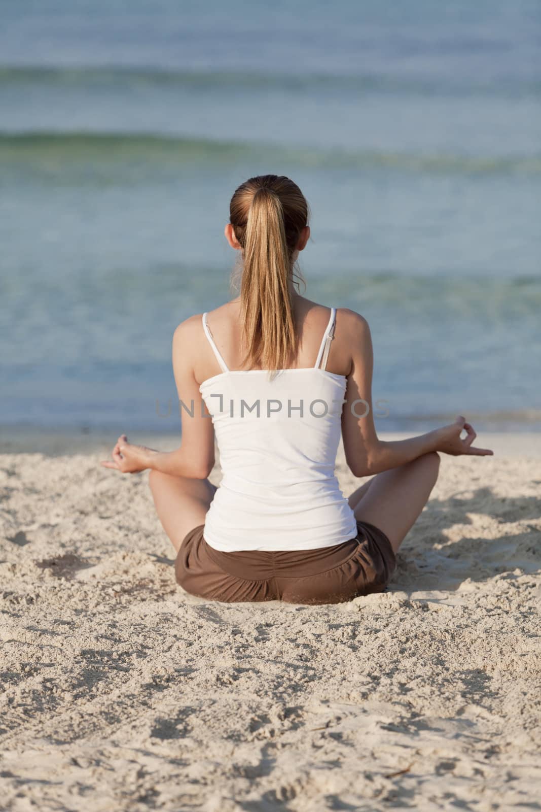 Young sporty woman doing sport yoga on the beach in the sand on the beach in the sun