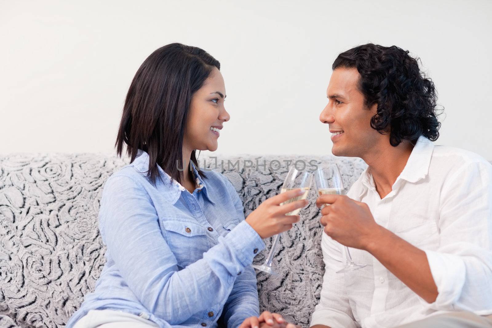 Young couple having sparkling wine on the sofa