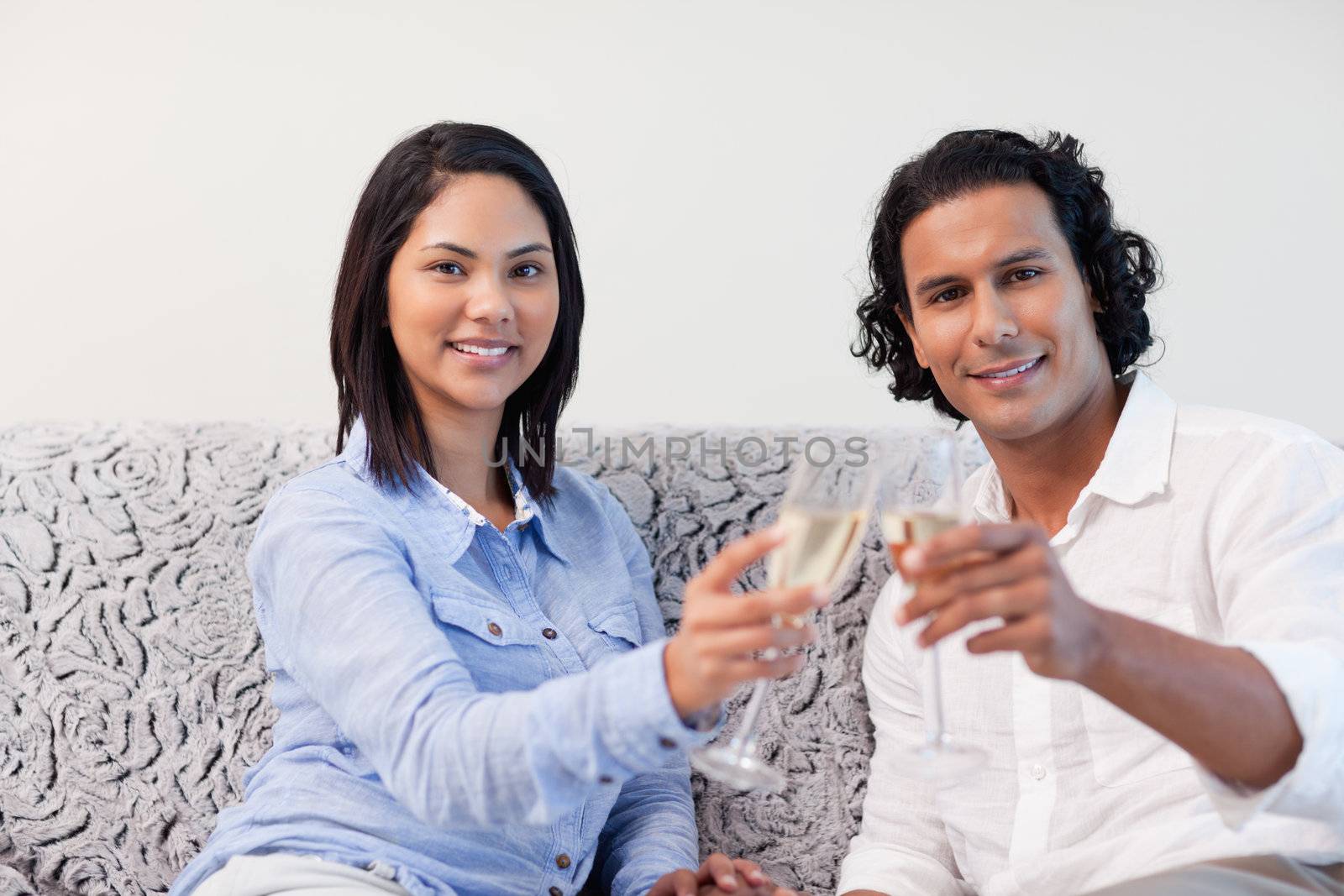 Young couple celebrating with sparkling wine on the sofa
