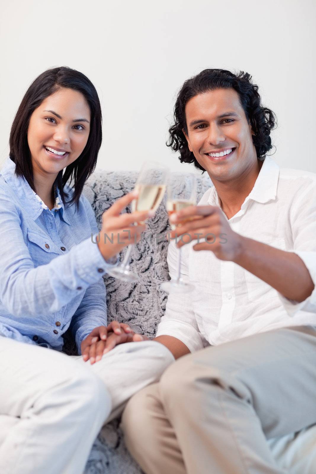 Happy young couple drinking sparkling wine on the sofa