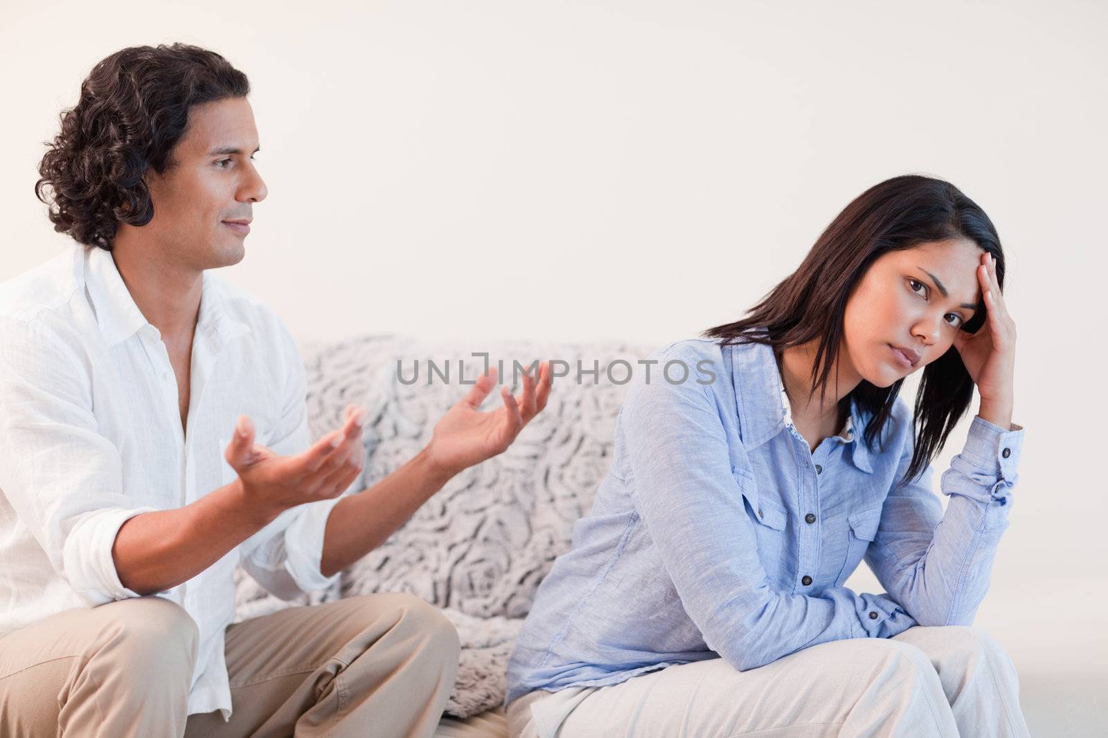 Young man on the sofa trying to apologize to his girlfriend
