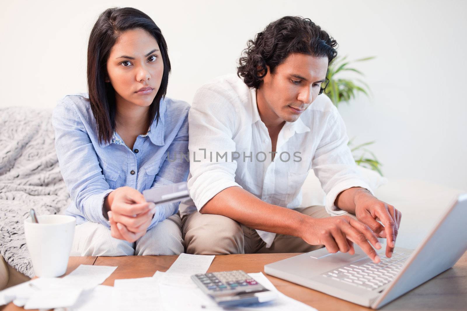 Young couple checking their bank accounts online in the living room
