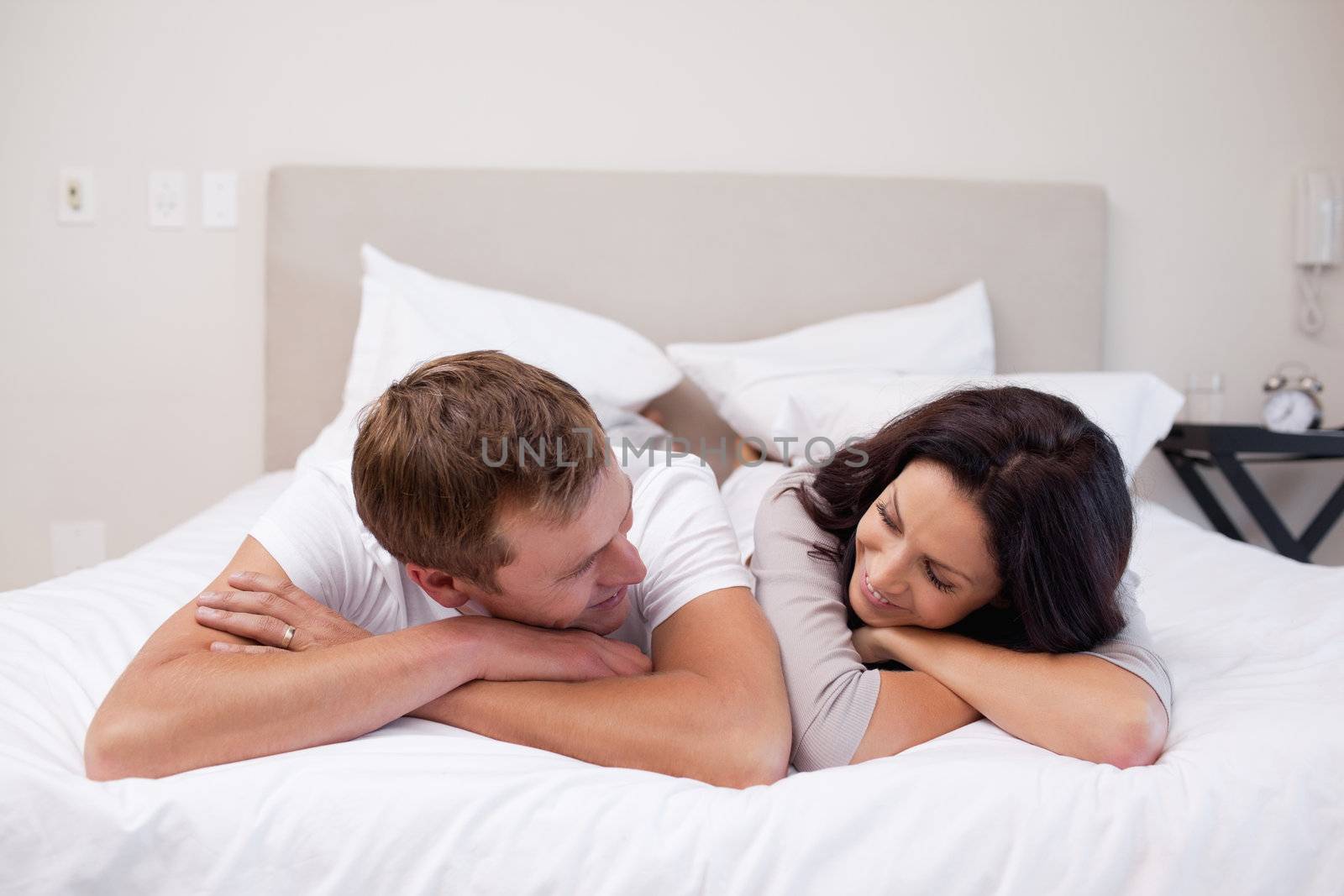 Young couple laying on the bed looking at each other