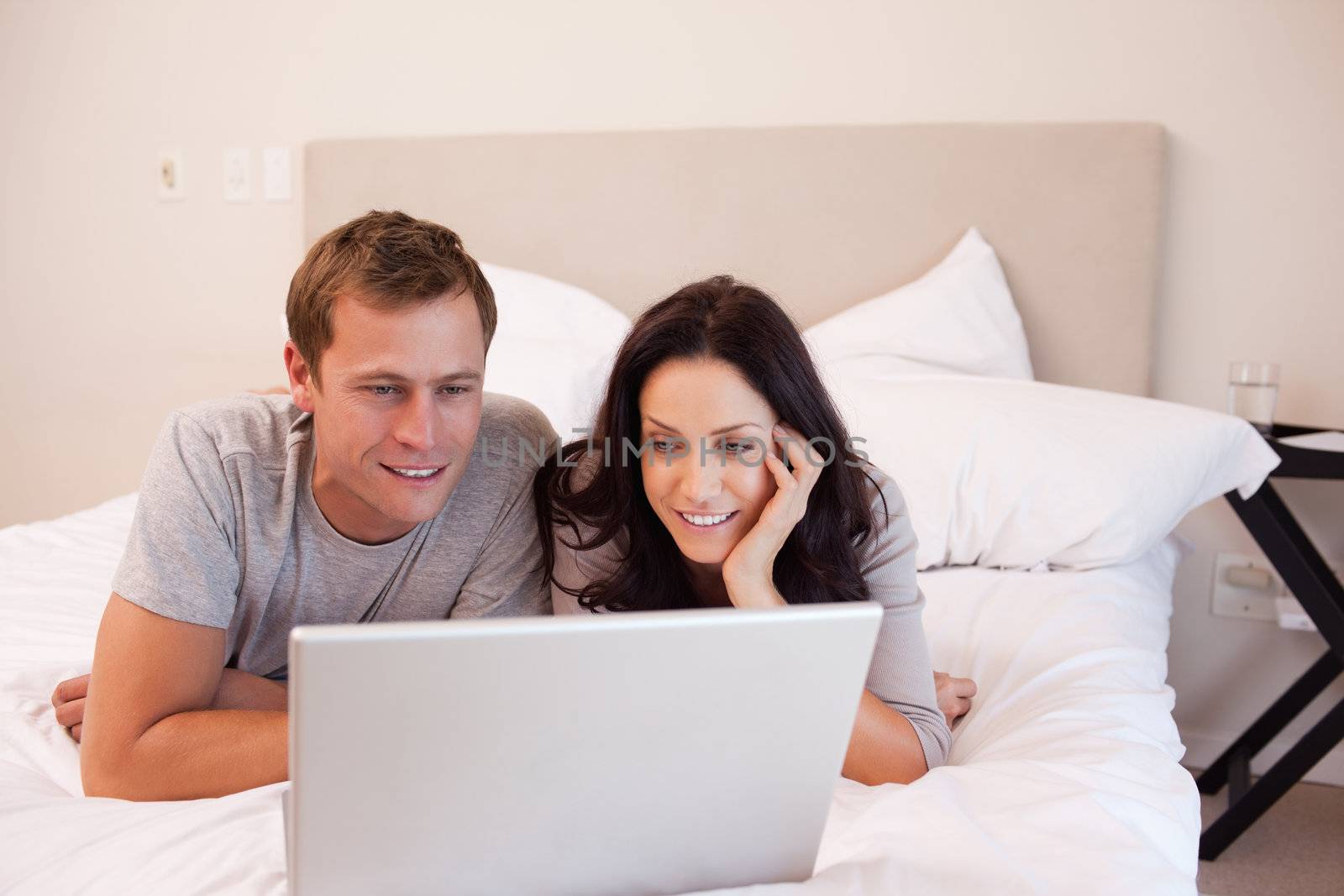 Young couple using laptop on the bed together