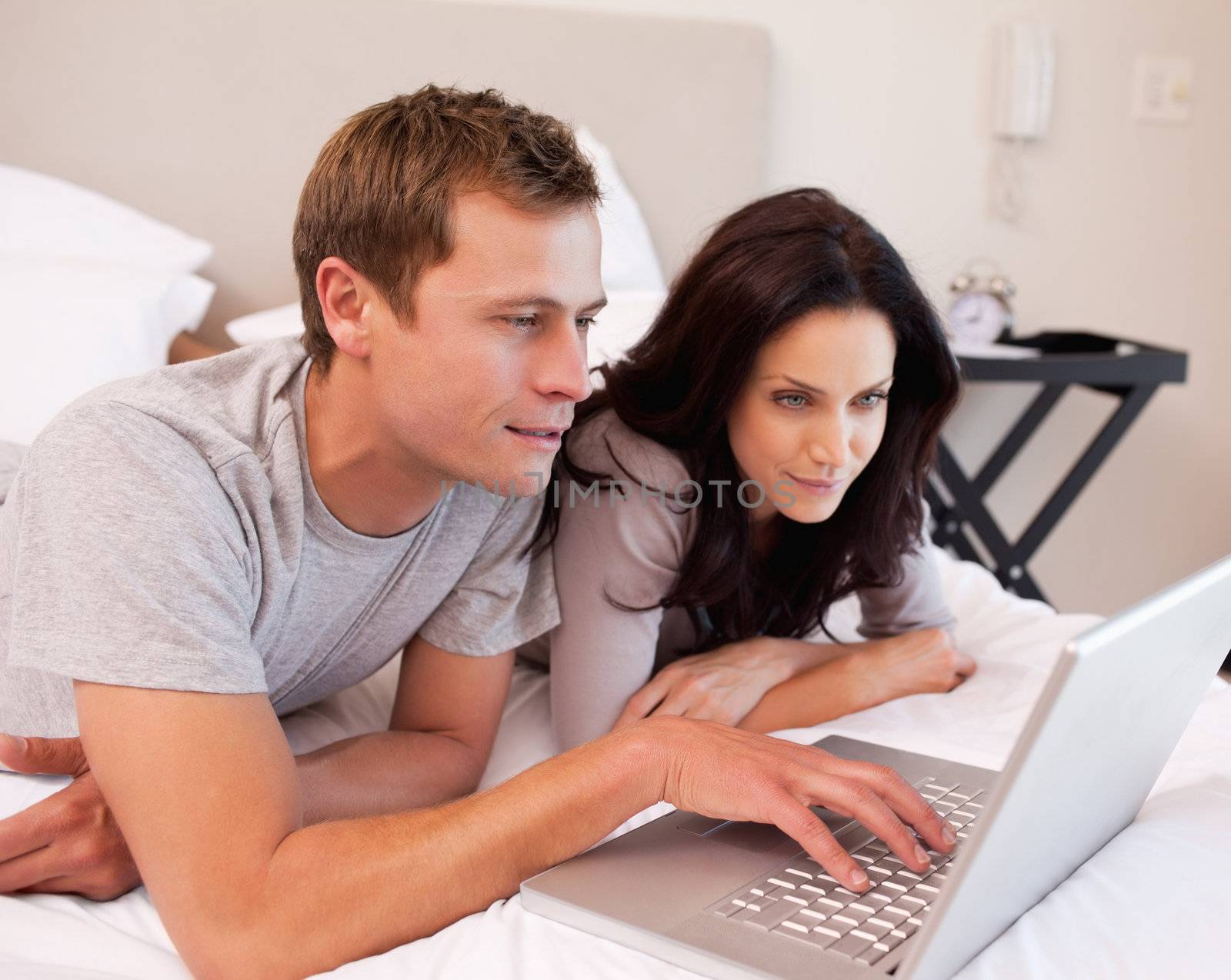 Young couple using notebook together in the bedroom
