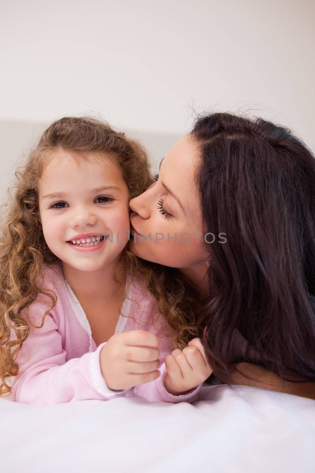 Young mother giving her little daughter a kiss