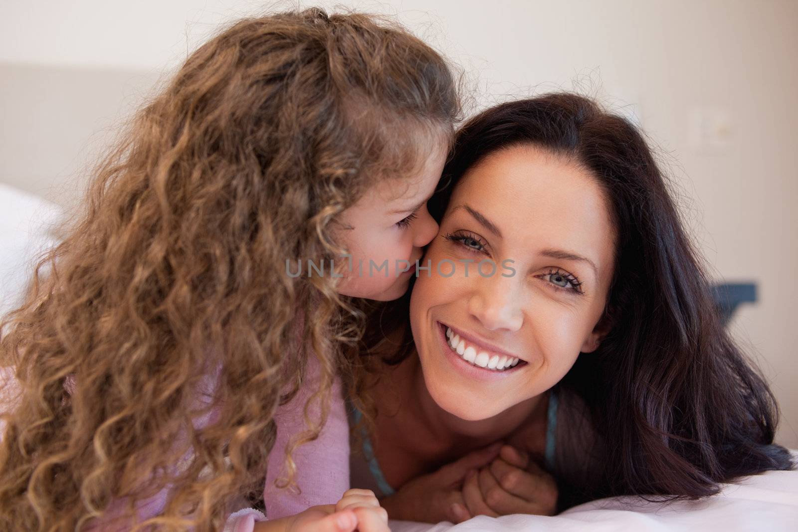 Little daughter giving her young mother a kiss