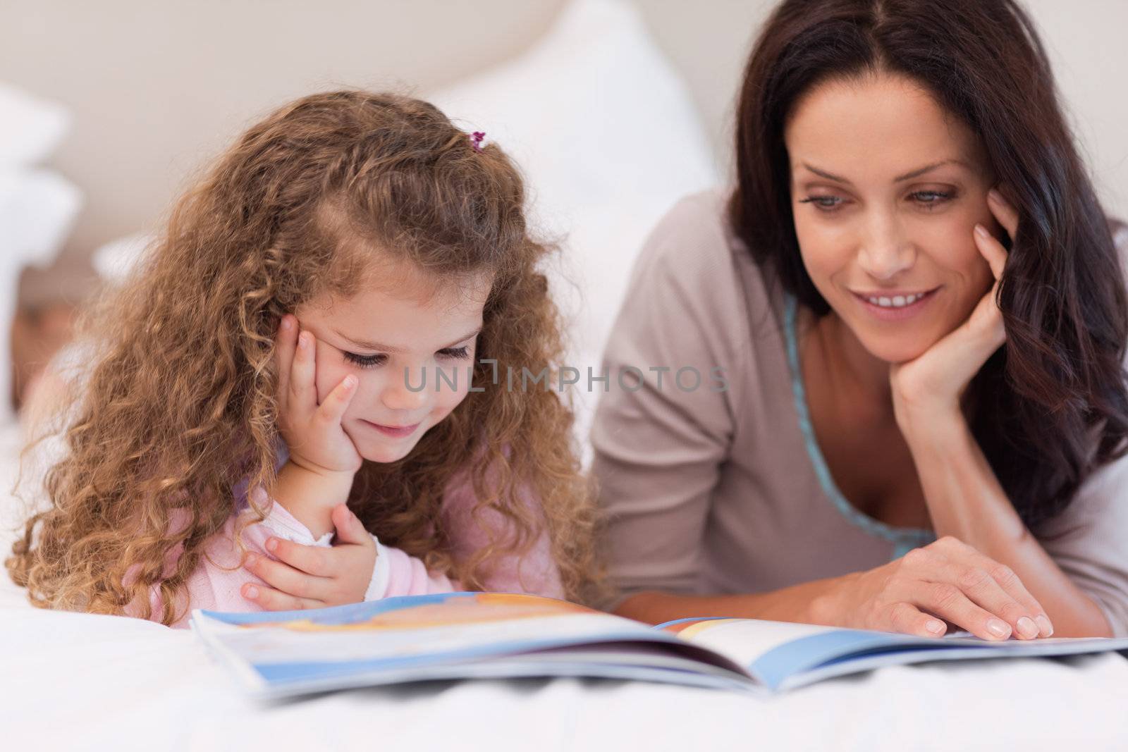 Little girl reading bedtime story with her young mother