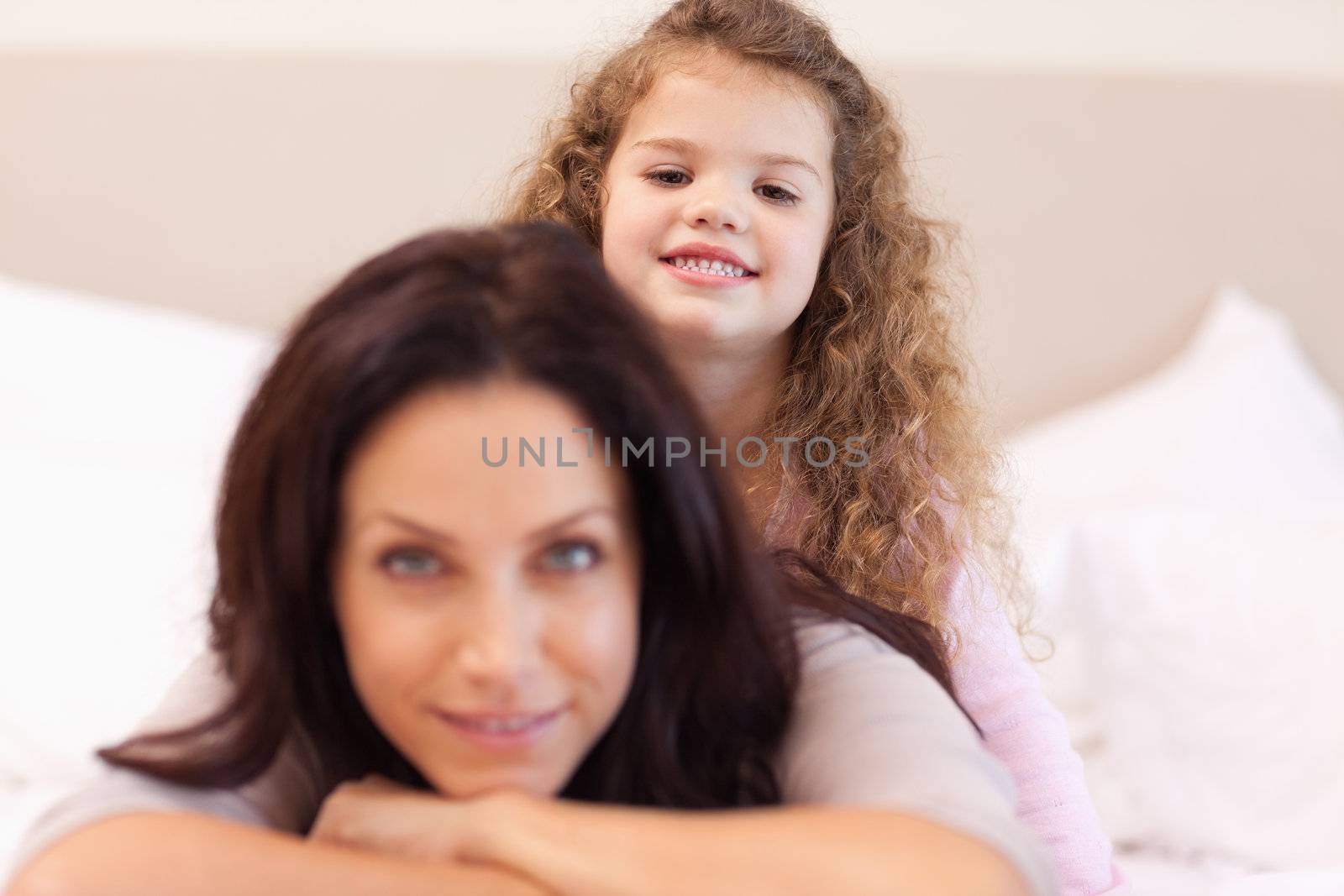 Smiling little girl sitting on her mothers back