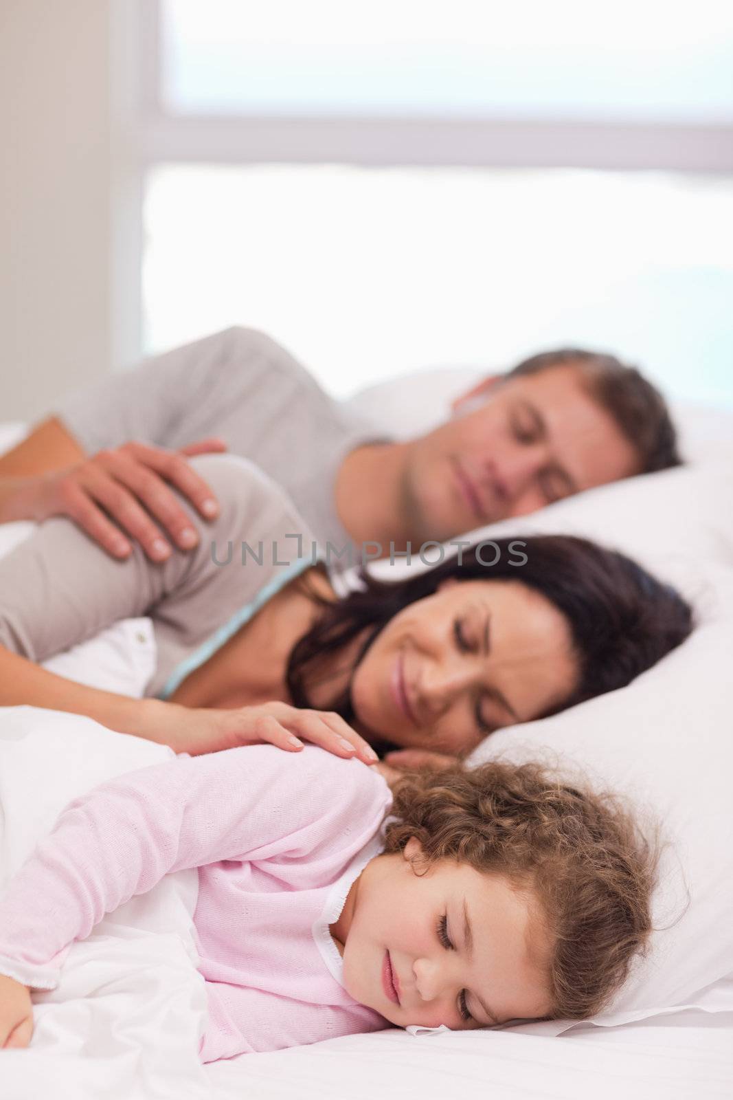 Family sleeping on the bed by Wavebreakmedia