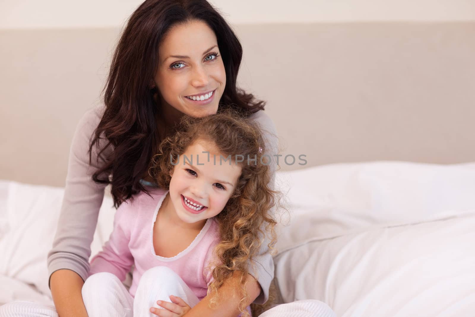 Young mother hugging her daughter on the bed