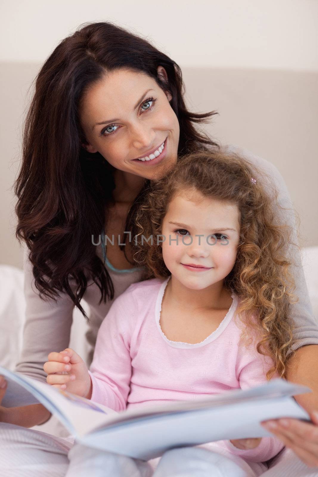 Smiling young mother reading a bedtime story with her little daughter
