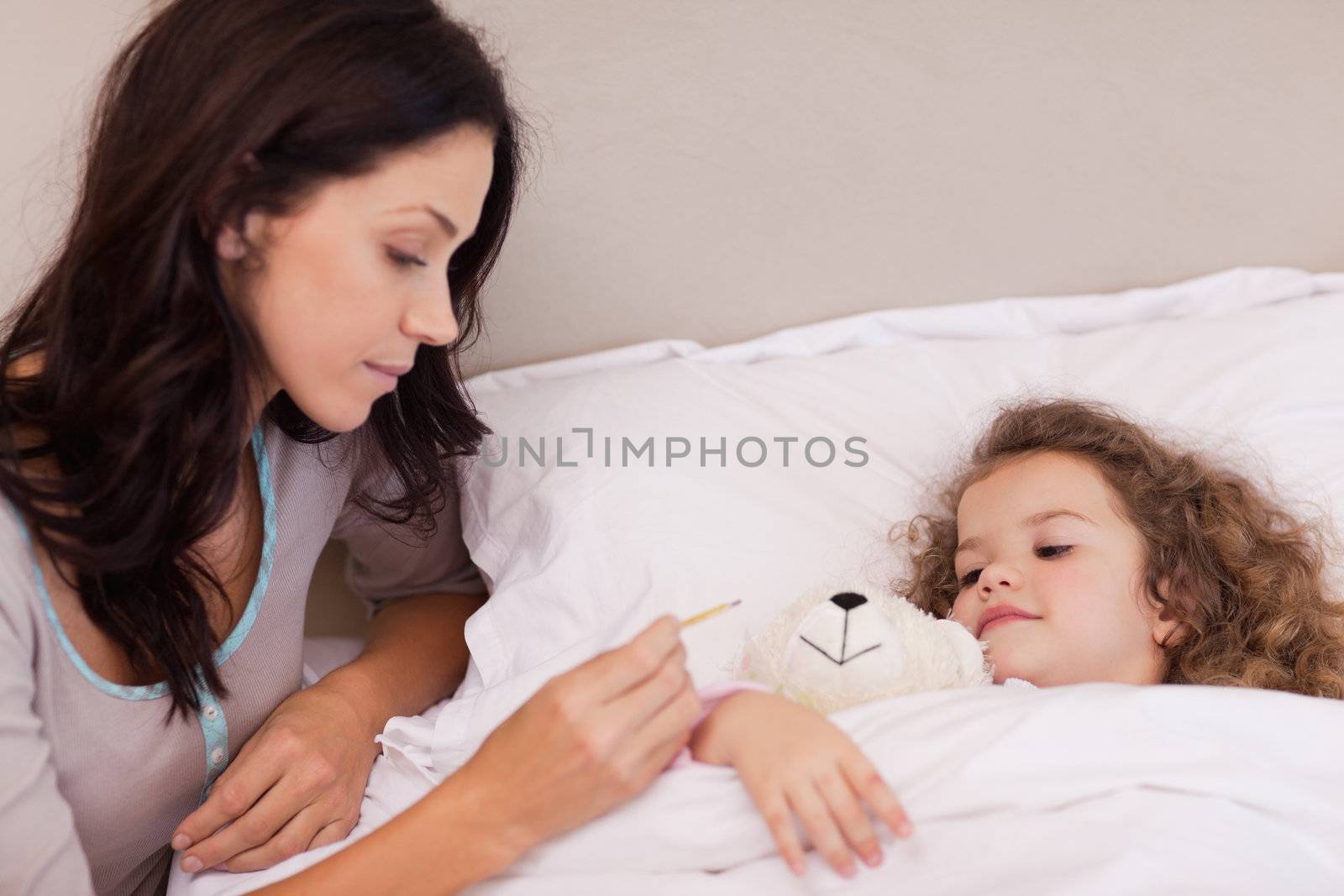 Young mother taking her daughters temperature