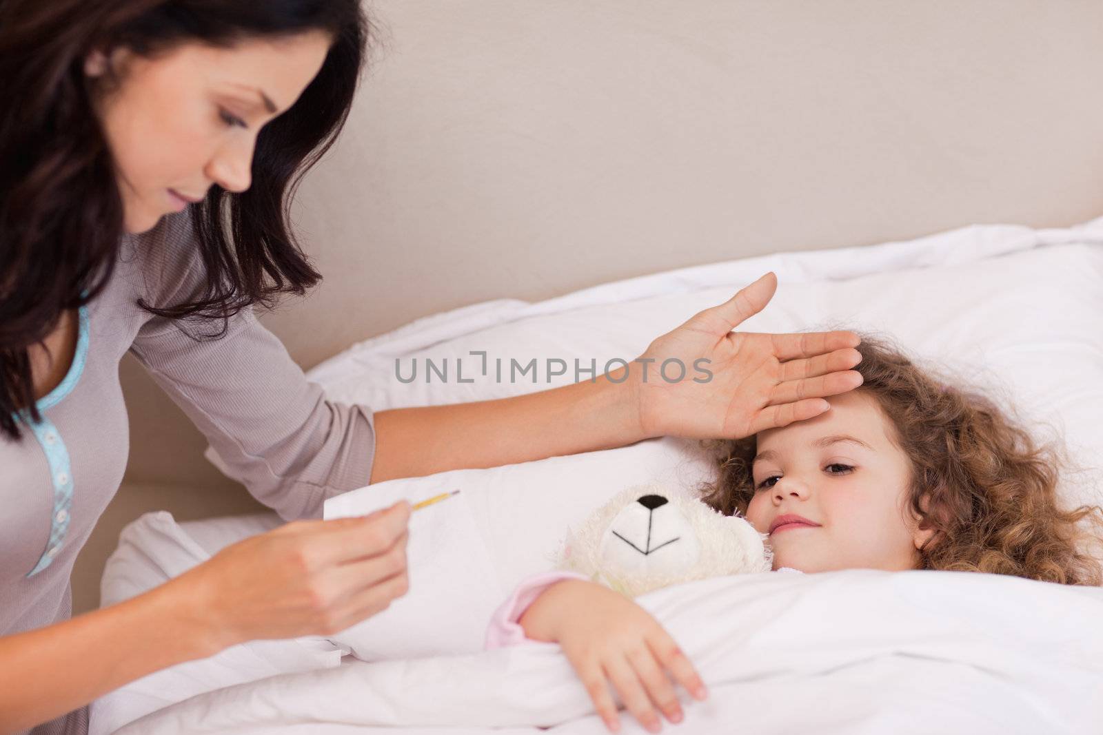 Young mother measuring her daughters temperature