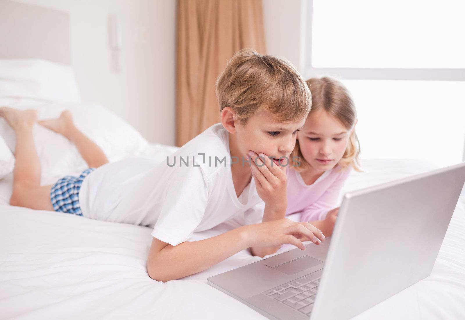 Children using a laptop in a bedroom