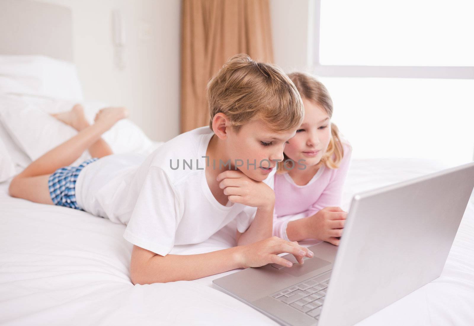 Children using a notebook in a bedroom