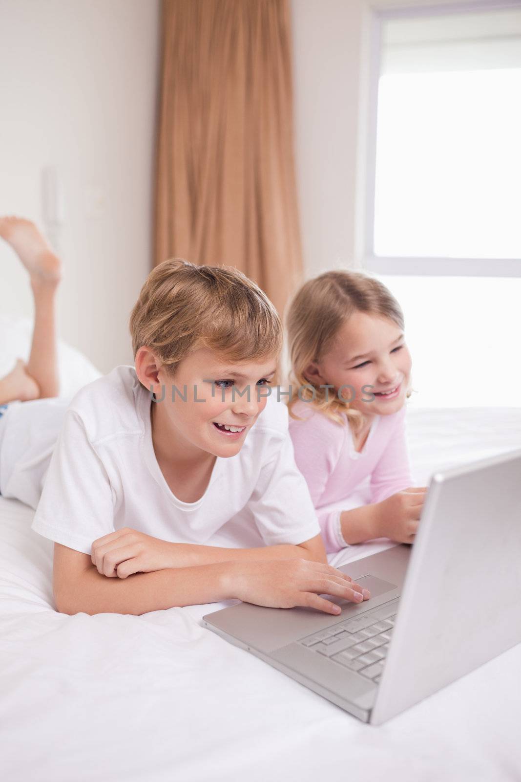 Portrait of children using a notebook in a bedroom