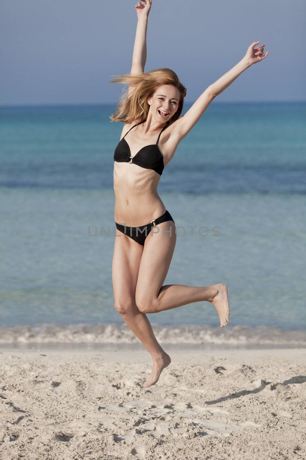 Young woman with bikini girl jumping at the beach with blue sky on the sea in summer vacation