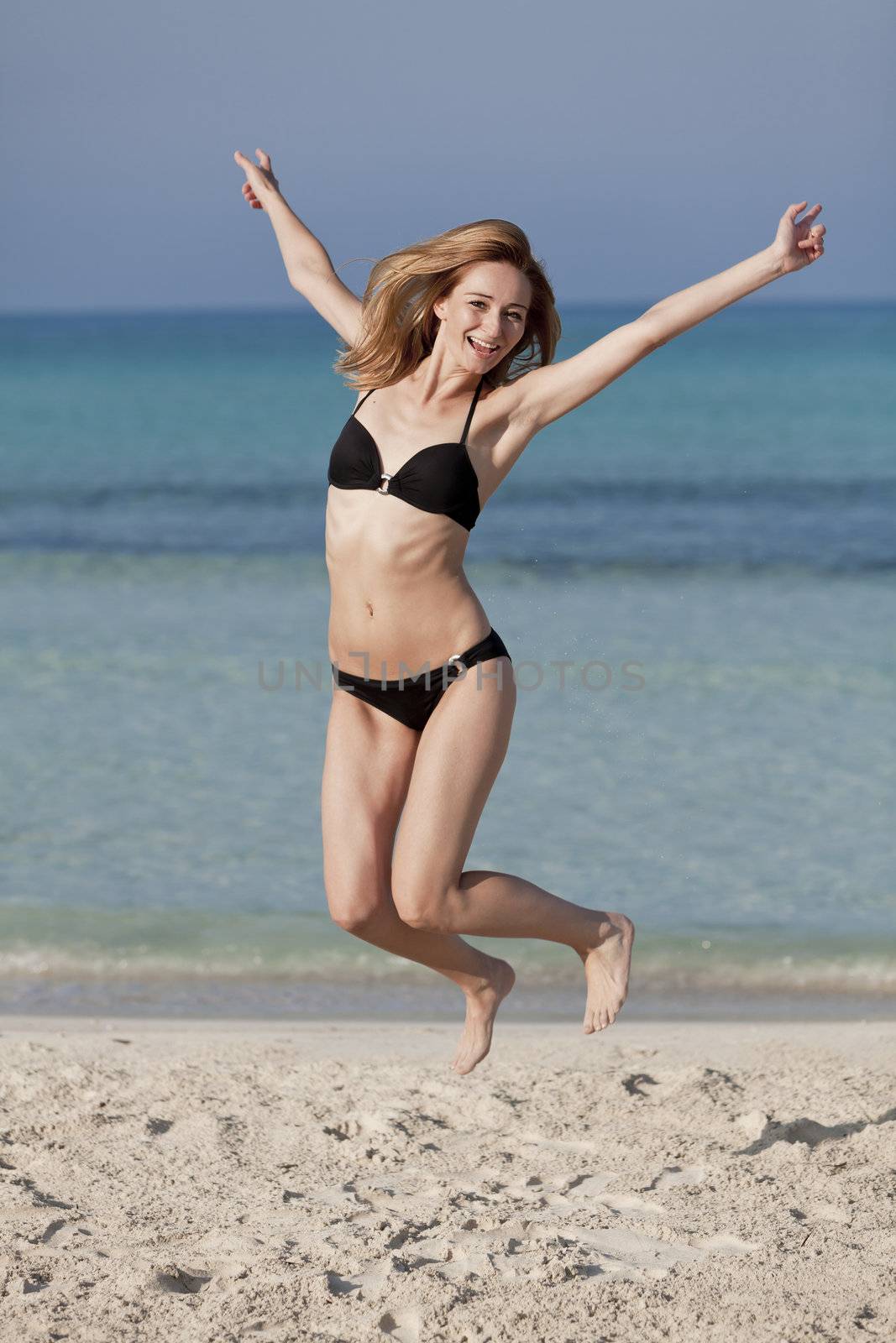 Young woman with bikini girl jumping at the beach with blue sky on the sea in summer vacation