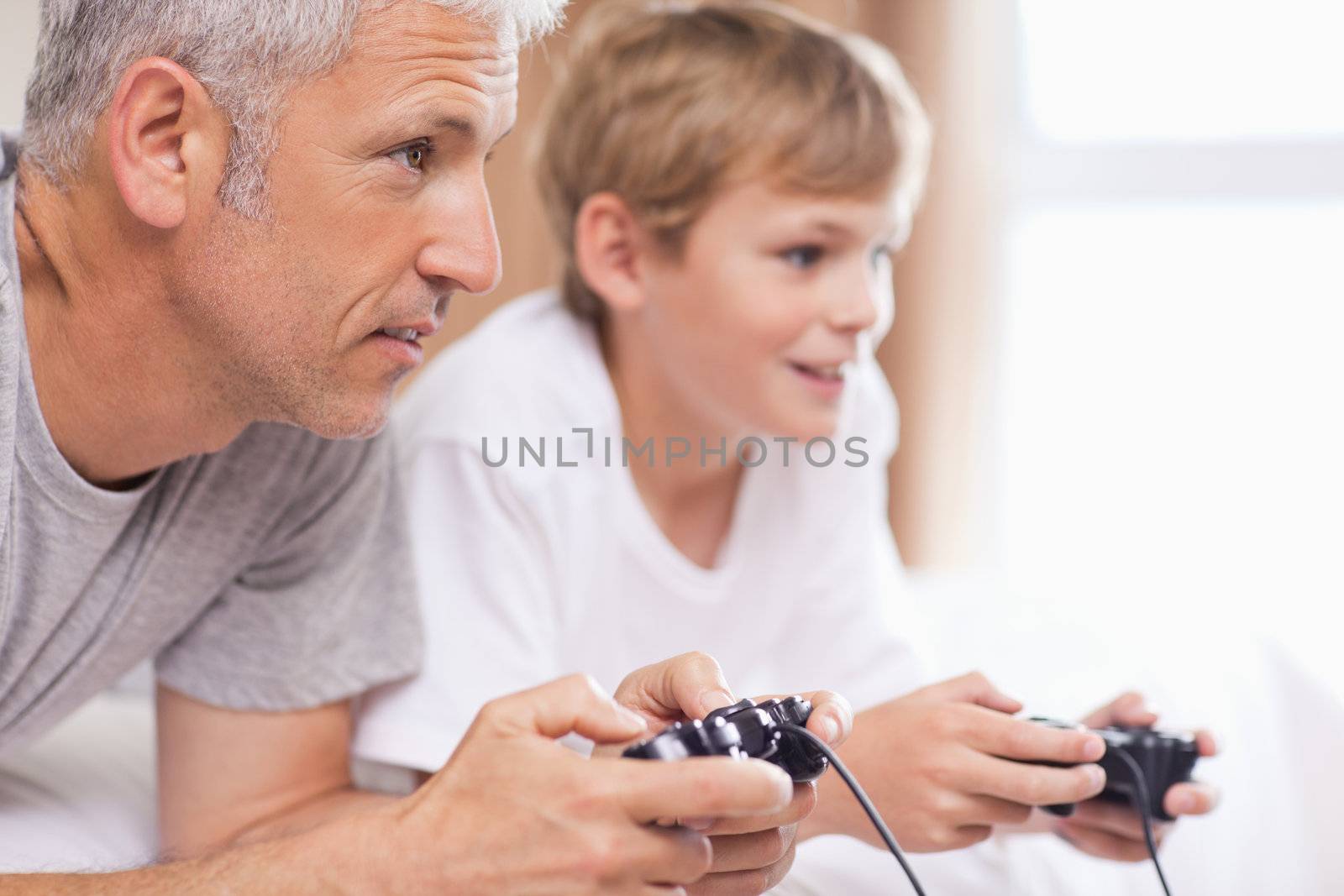 Father playing video games with his young son in a bedroom