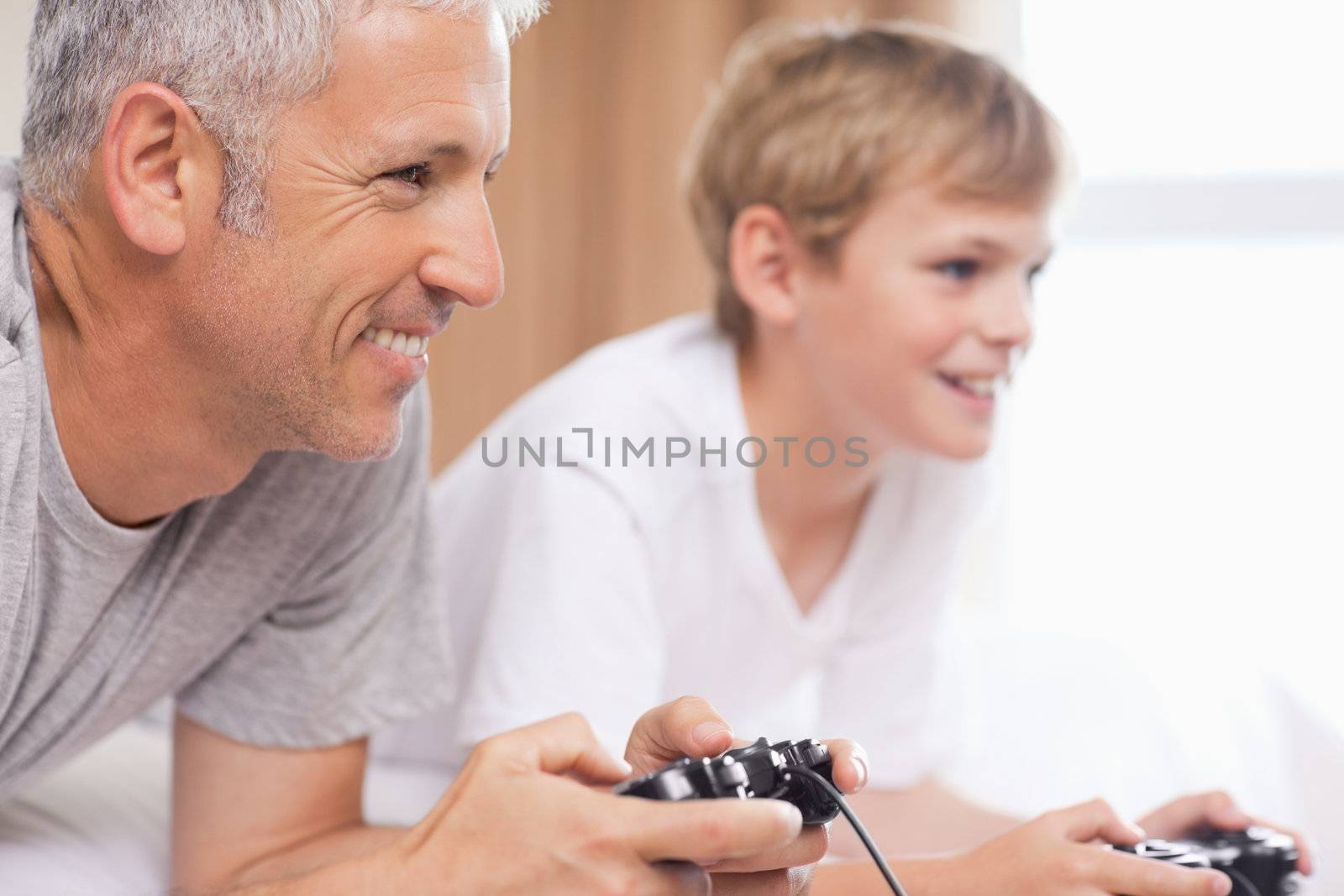 Father and his son playing video games in a bedroom
