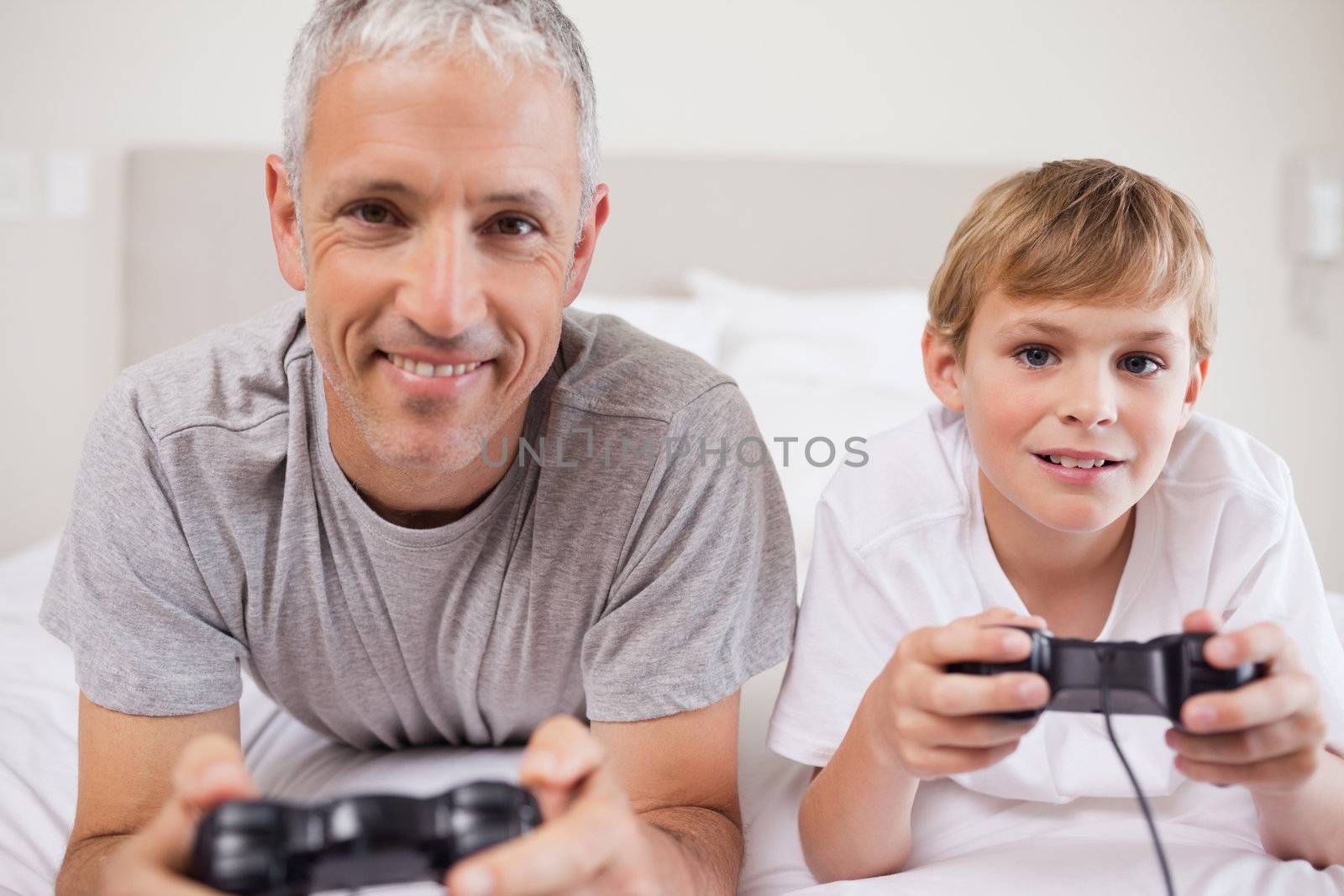 Boy and his father playing video games in a bedroom