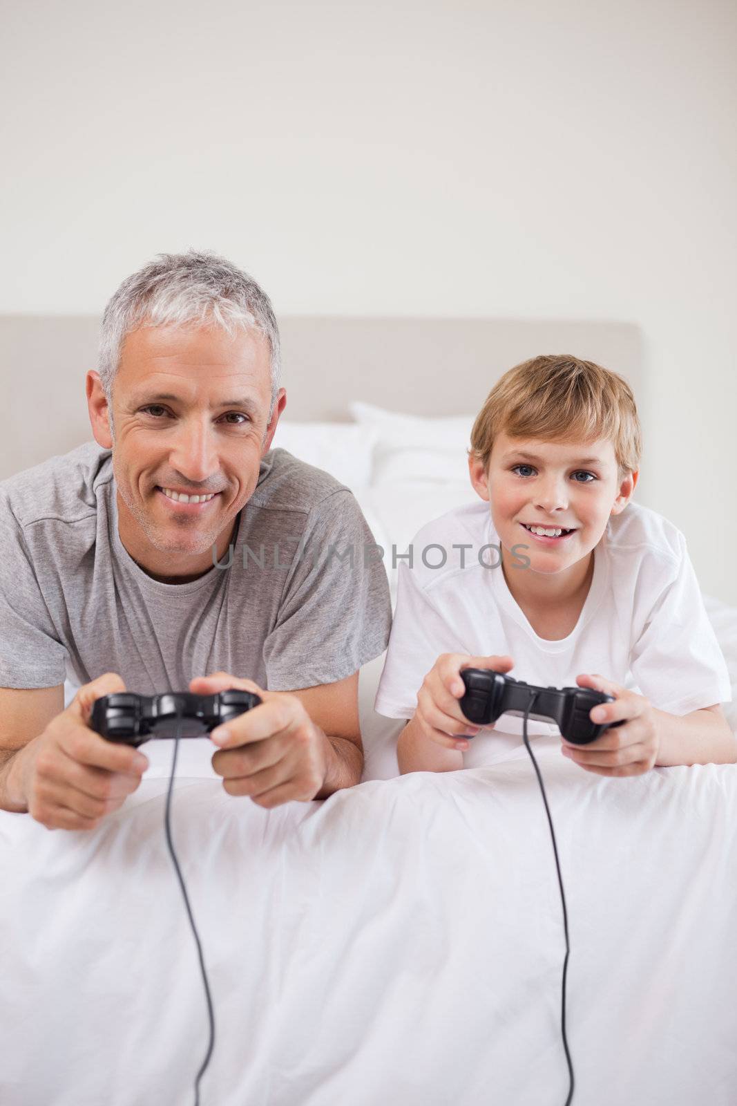 Portrait of a boy and his father playing video games in a bedroom