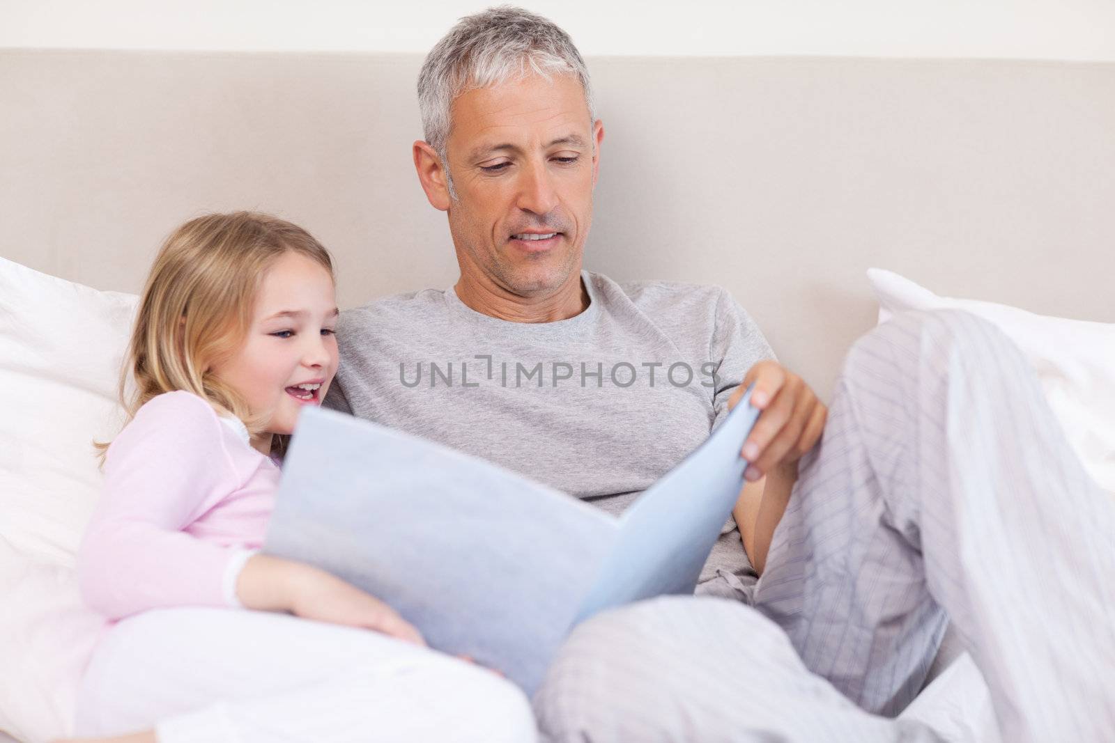 Father reading a story to his daughter in a bedroom
