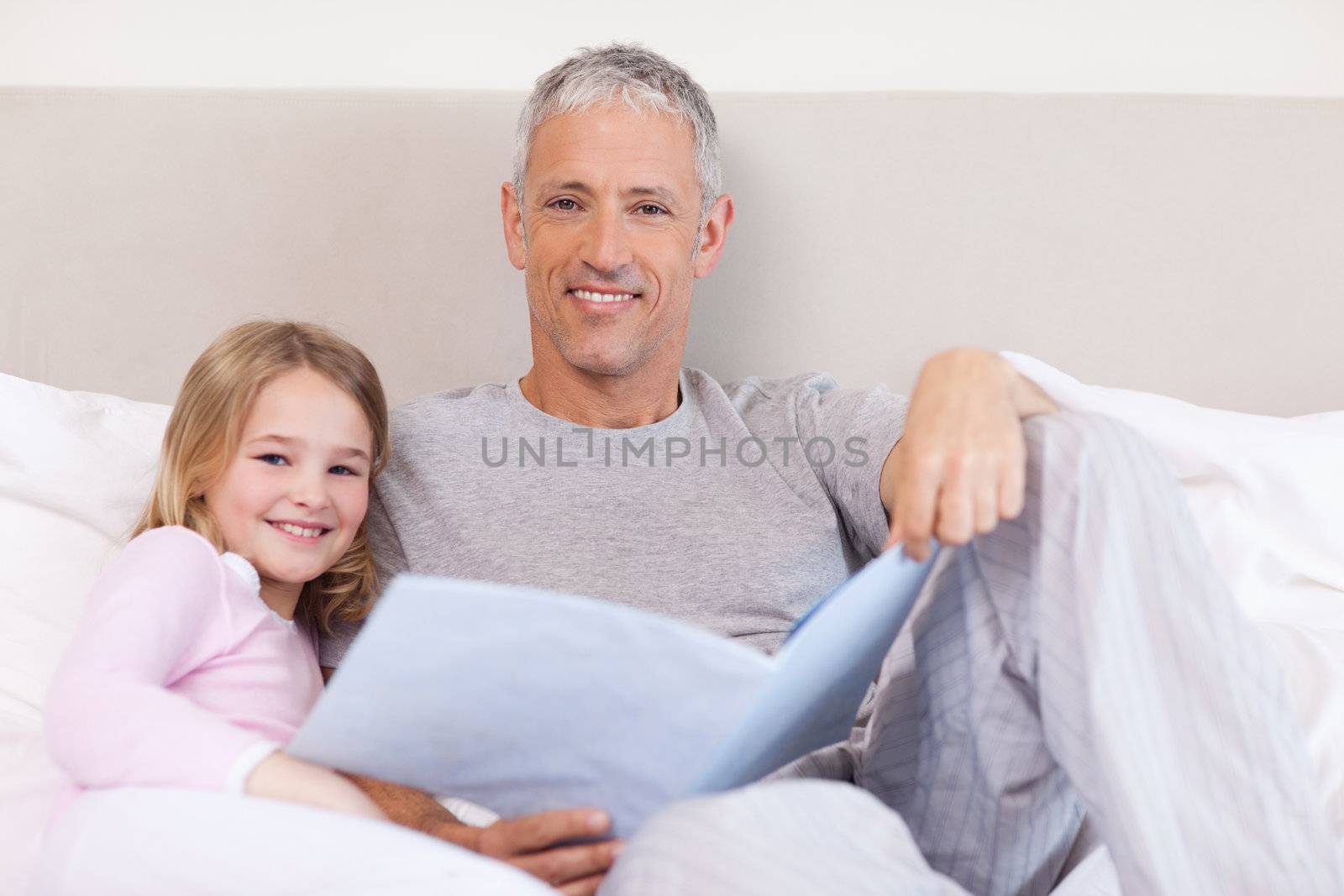 Smiling father reading a story to his daughter in a bedroom