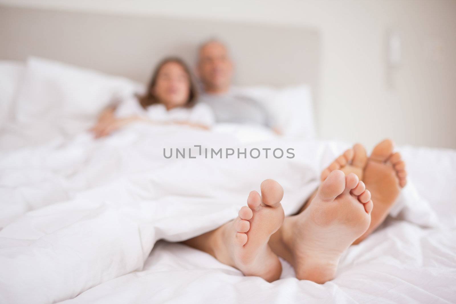Couple lying in a bed with the camera focus on their feet