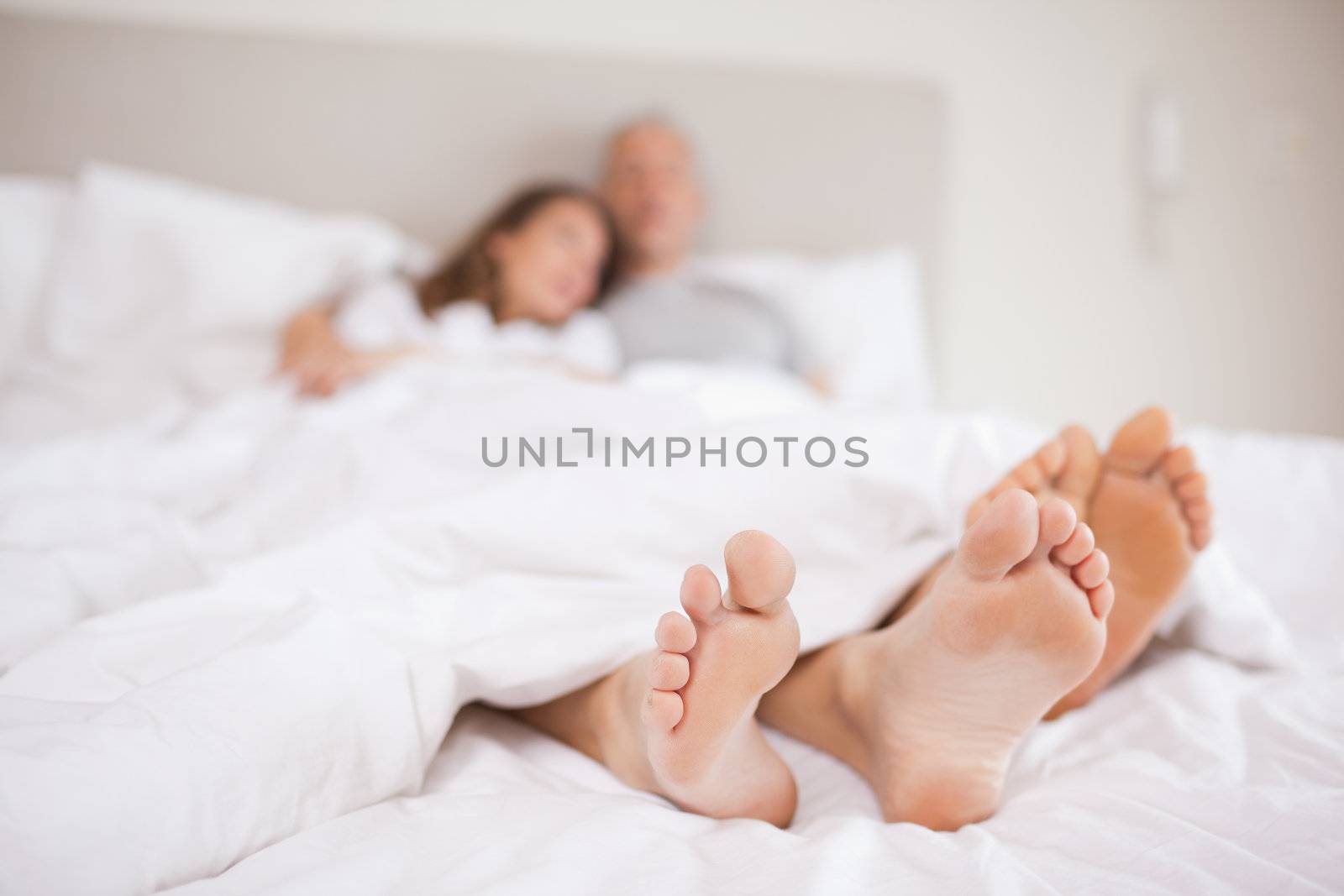 Lovely couple lying in a bed with the camera focus on their feed