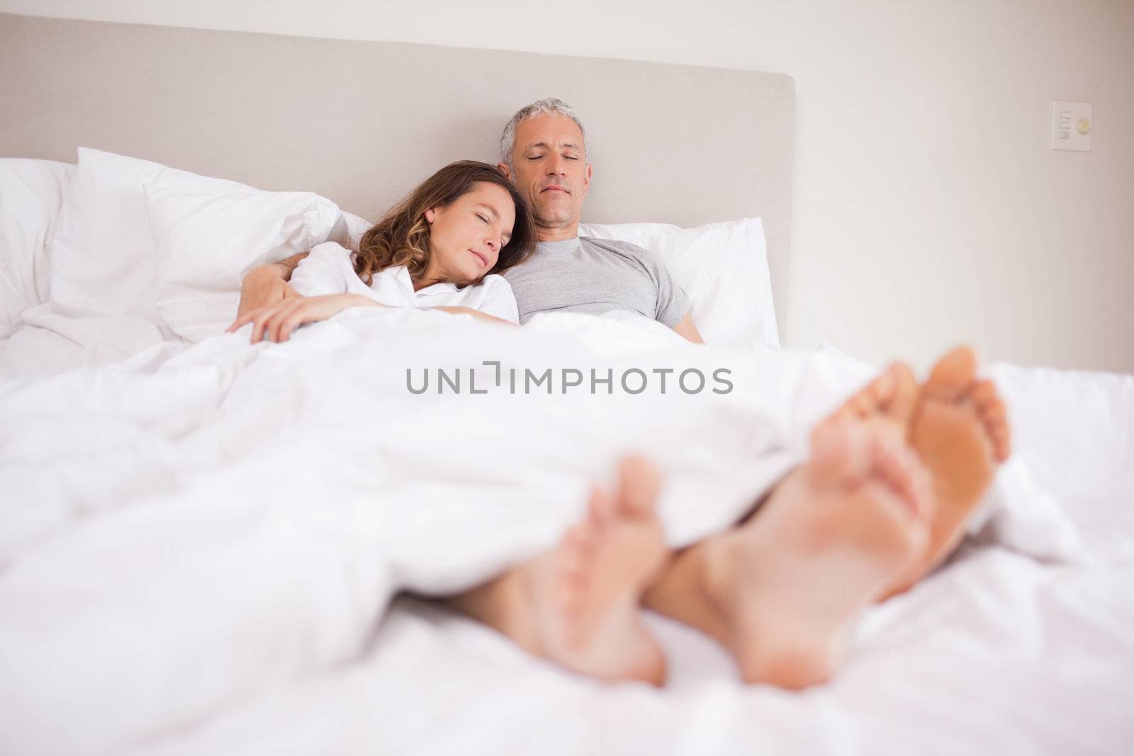 Couple sleeping in their bedroom with their eyes closed