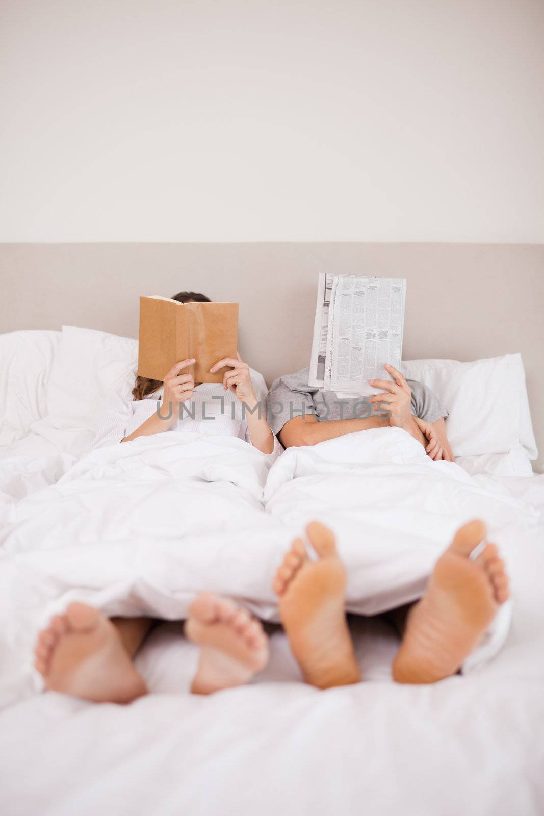Portrait of playful couple reading in their bedroom