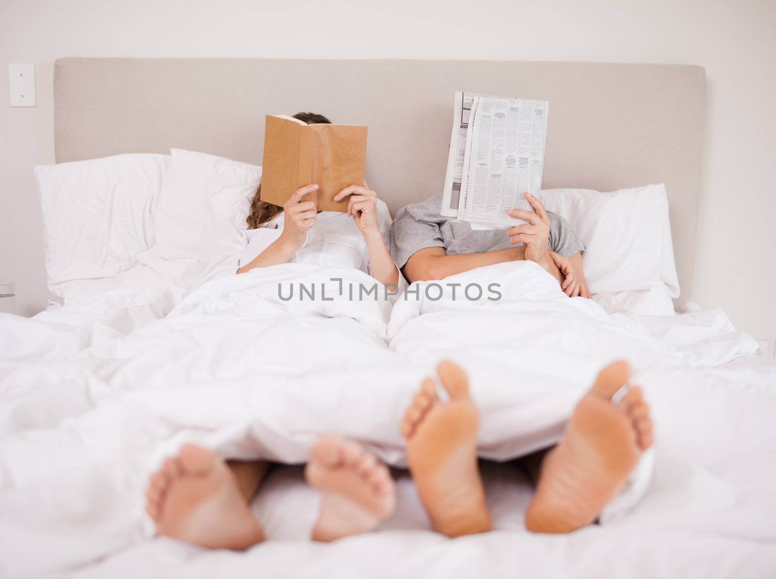Playful couple reading in their bedroom