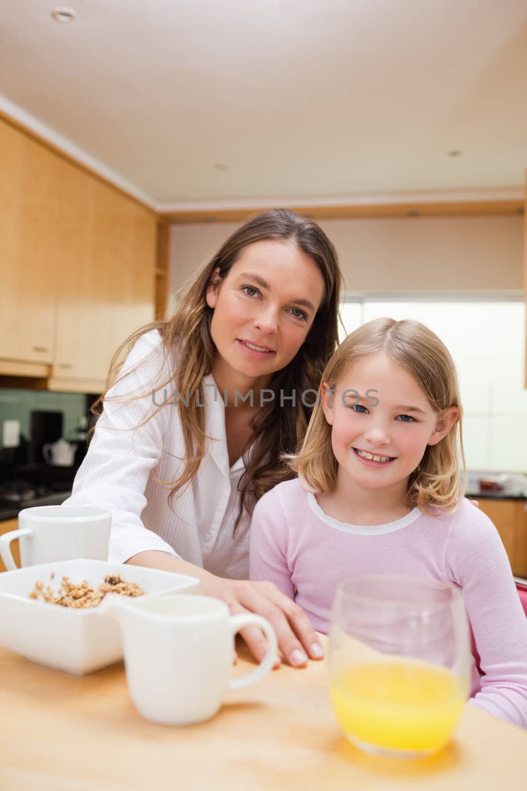 Portrait of a happy mother and her daughter having breakfast in a kitchen