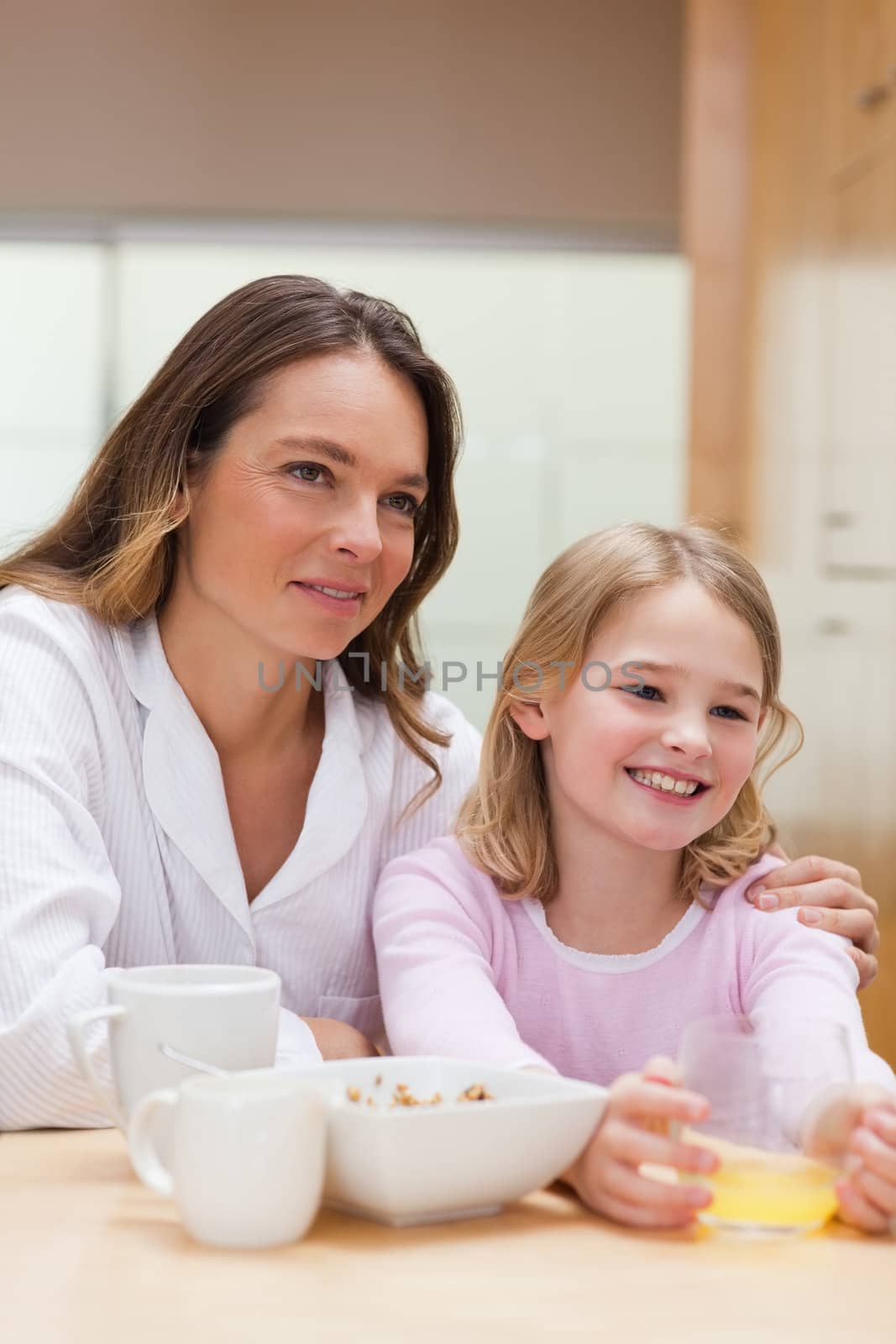 Portrait of a beautiful mother and her daughter having breakfast in a kitchen