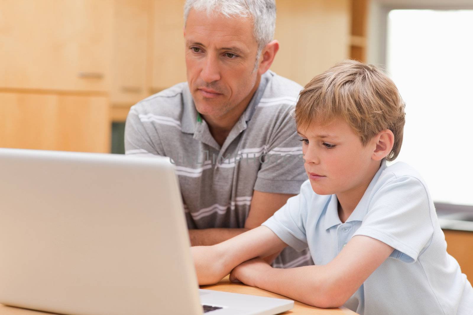 Boy and his father using a laptop in a kitchen